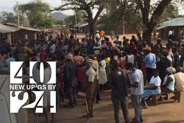 a group of African men and women sit and stand at an outdoor gathering